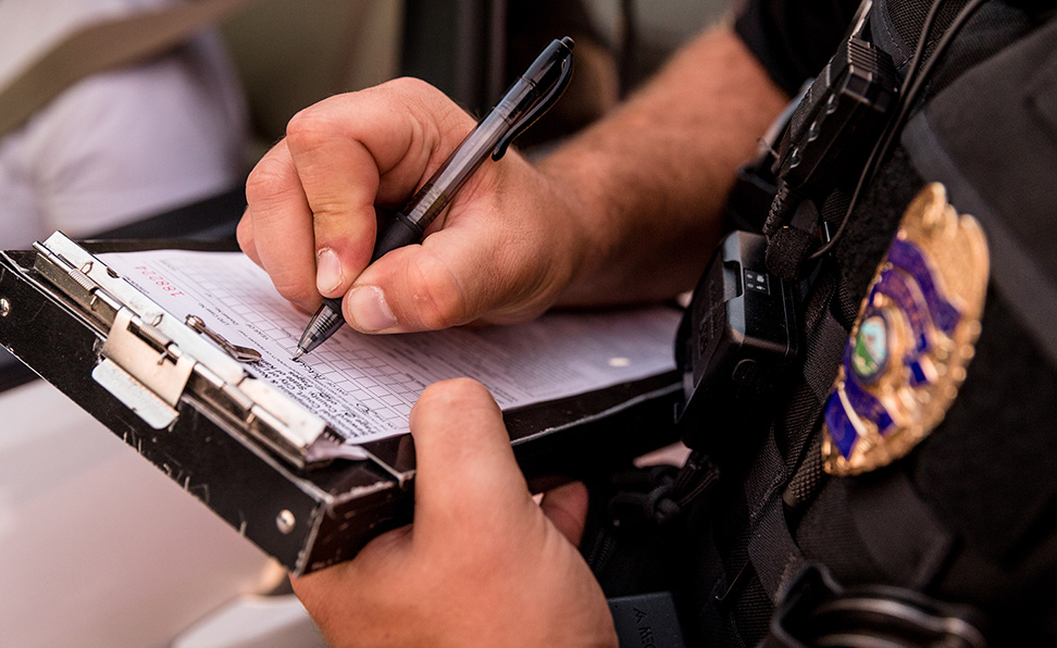 A law enforcement officer writes a ticket at a traffic stop